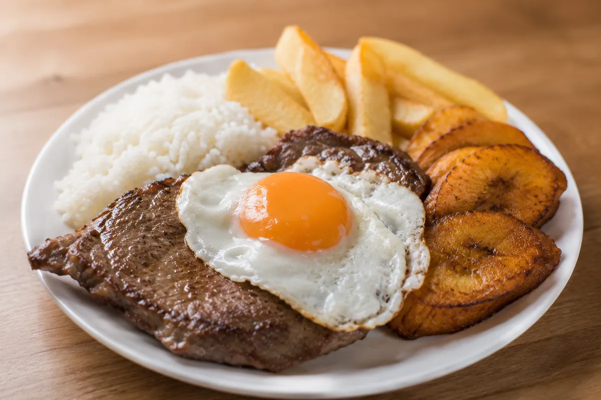 Bistec a lo pobre, steak with fried egg, rice, fries and plantain